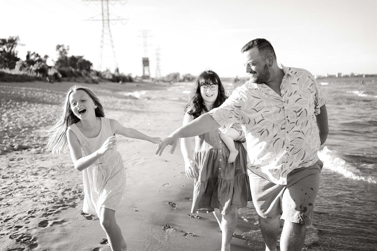 A family of four walking down the beach with the water on their left.