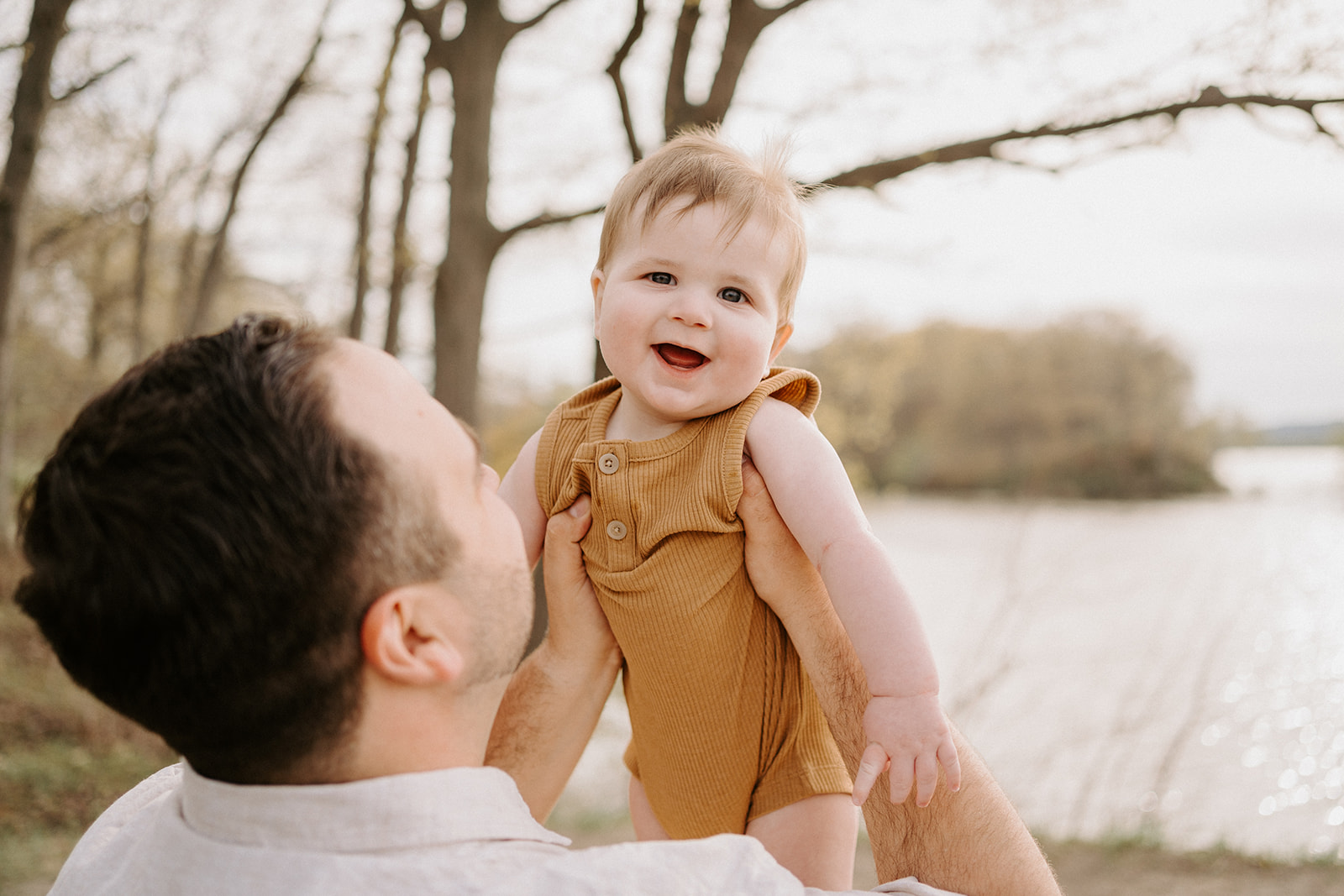 A toddler being held up by a man.