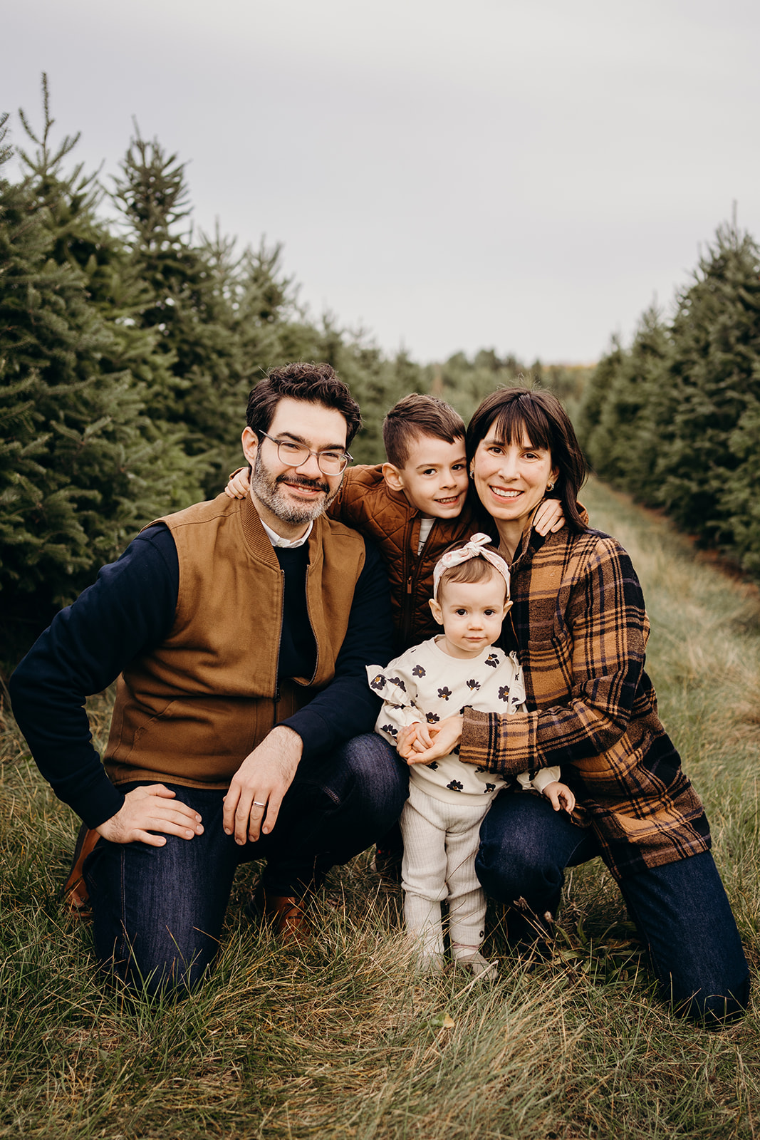 A family of four kneeling on the grass smiling.