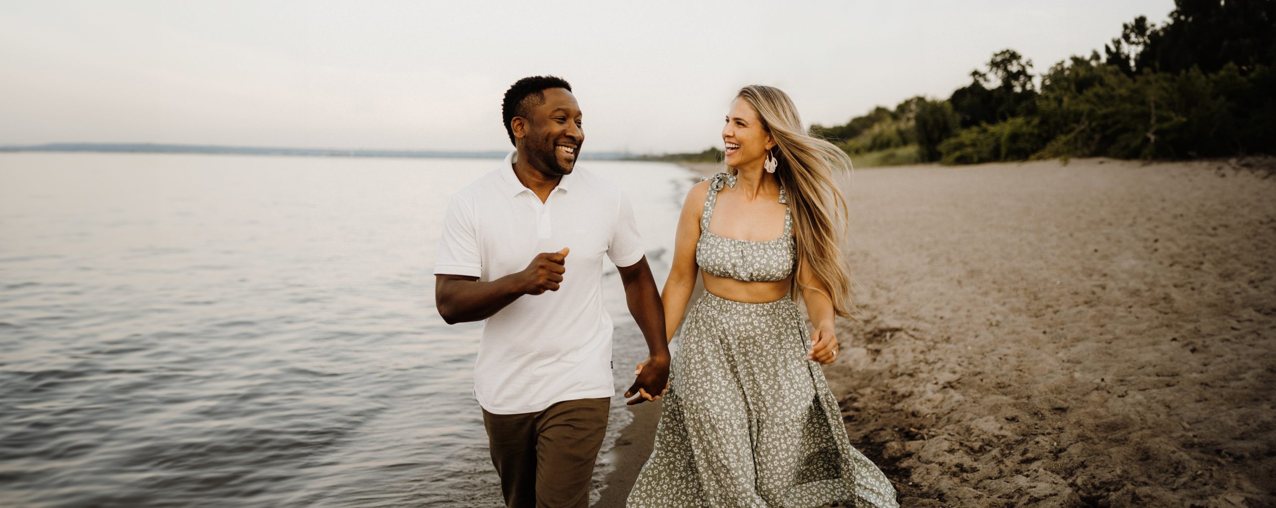 Man and woman holding hands walking down the beach.